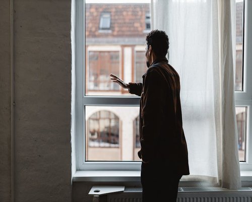 Person standing near a window looking outside
